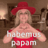 a woman in a red hat is making a heart with her hands