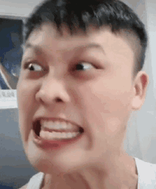 a young man is making a funny face with his mouth open and his teeth showing .