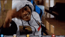 a man wearing a hoodie is smiling while sitting in a blue chair