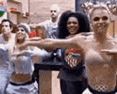 a group of people are standing next to each other and dancing in a room .