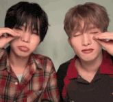 two young men are making funny faces with their eyes closed and one of them is wearing a plaid shirt