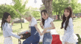 a group of young women are dancing in a park while holding hands .