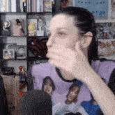 a woman wearing a purple shirt with a picture of a girl on it is talking into a microphone .