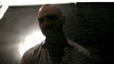 a man with a shaved head wearing a white shirt
