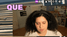 a woman wearing headphones looks at a screen that says que on it