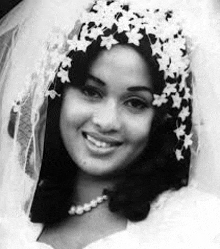 a black and white photo of a woman wearing a wedding dress and veil .