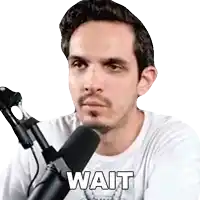 a man in a white shirt is sitting in front of a microphone with the word wait written on it