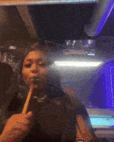 a woman is smoking a hookah in a dark room with a pool table in the background