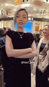 a woman in a purple dress is standing with her arms crossed in front of a bvlgari sign