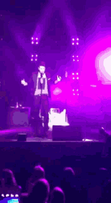 a man is standing on a stage with purple lights behind him