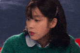 a woman in a green sweater holds a chopstick to her mouth