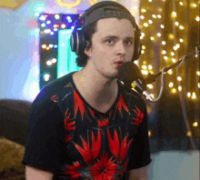 a man wearing headphones and a red and black shirt is talking into a microphone