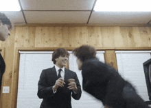 a man in a suit and tie is talking to another man in a room