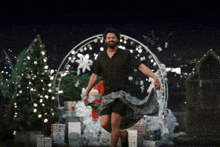 a man is dancing in front of a christmas tree while wearing a skirt .