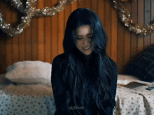 a woman with long black hair is sitting on a bed with christmas decorations
