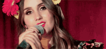 a woman wearing a flower in her hair singing into a microphone
