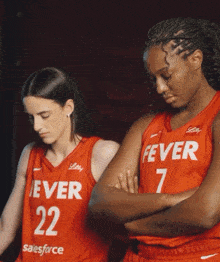 two female basketball players wearing red jerseys that say fever on them