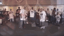 a group of men are standing in a room wearing white shirts that say ' sb ' on them