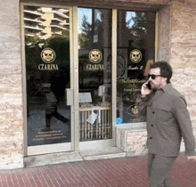 a man is talking on a cell phone in front of a store that says czarna