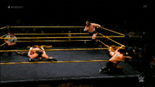 a wrestler is kicking another wrestler in the face while a referee watches