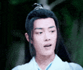 a young man with long black hair is wearing a white kimono .