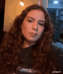 a woman with long curly hair is taking a selfie in a kitchen .