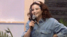 a woman wearing a face shield is speaking into a microphone .