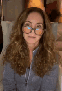 a woman wearing glasses is sitting in a chair with the letter l on the left