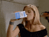 a woman is drinking from a carton of kathy milk