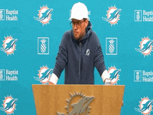 a man stands at a podium in front of a banner that says baptist health