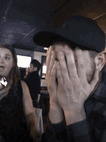 a man covering his face with his hands while a woman watches