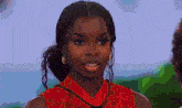 a woman is wearing a red dress and earrings and looking at the camera .