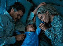 a man and a woman laying in bed with a baby .