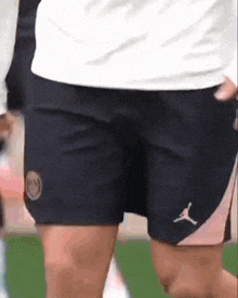 a person wearing a white shirt and black shorts with a logo on them .