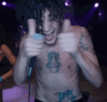 a shirtless man with a tattoo on his chest is giving two thumbs up
