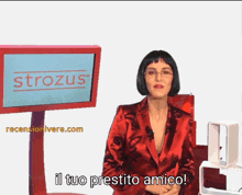 a woman in a red jacket is standing in front of a strozus sign