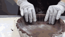a person wearing white gloves is making a pie