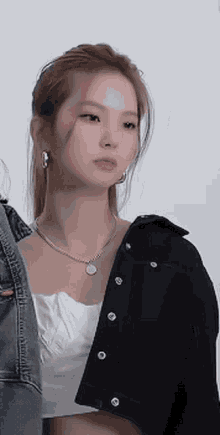 a close up of a woman wearing a necklace and a black jacket