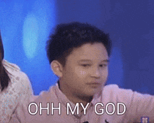 a young boy in a pink shirt is making a funny face with the words ohh my god above him