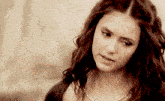 a woman with curly hair wearing a necklace