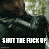 a close up of a man holding a gun with the words shut the fuck up above him .