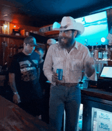 a man in a cowboy hat is standing in front of a bud light refrigerator