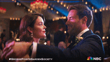 a man and a woman are dancing in front of a sign that says nbc on it