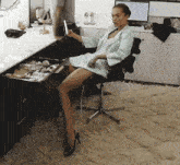 a woman sitting in a chair with her legs crossed looking at herself in a mirror