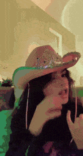 a woman wearing a cowboy hat is giving a thumbs up sign
