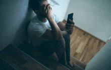 a man is sitting on the stairs using a cell phone .