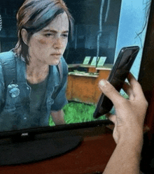 a person is holding a cell phone in front of an aoc monitor