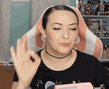 a woman sitting in a pink and white chair making an ok sign