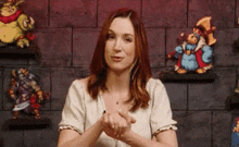 a woman is standing in front of a wall with cartoon characters on shelves and giving a thumbs up .