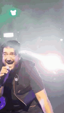 a man is singing into a microphone in front of a green light